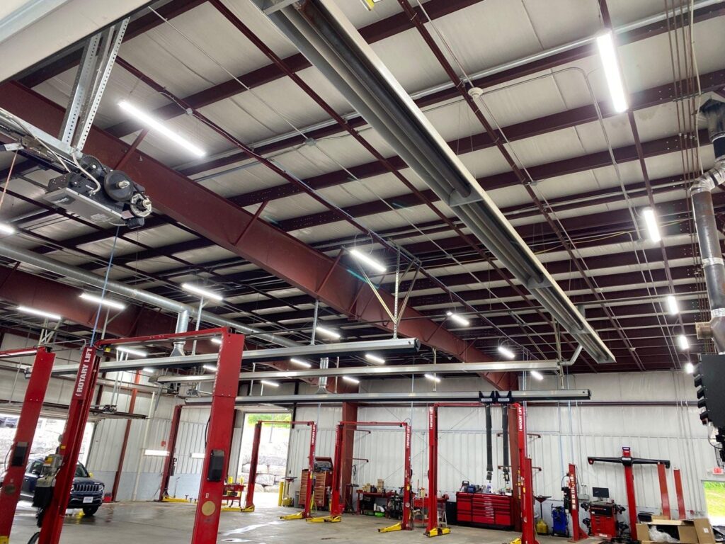 An automotive repair shop with upgraded bright LED lighting installed along the ceiling, enhancing visibility and energy efficiency in the workspace
