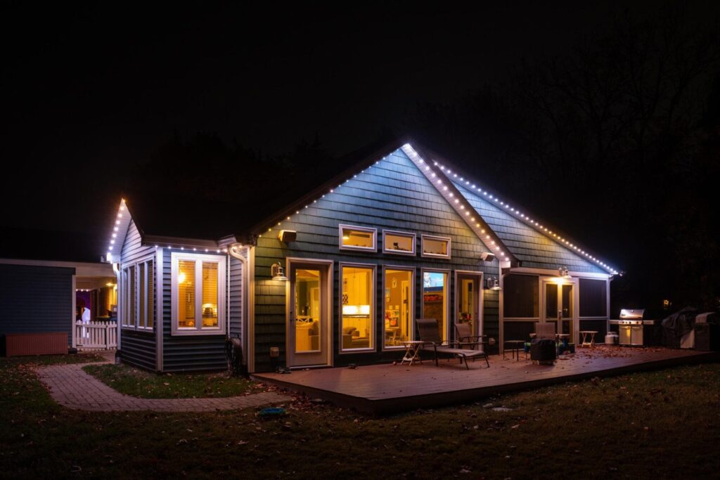 A house illuminated with Oelo permanent holiday lighting in white colors, showcasing a festive design. The lights are installed along the roofline, blending seamlessly with the house exterior at night