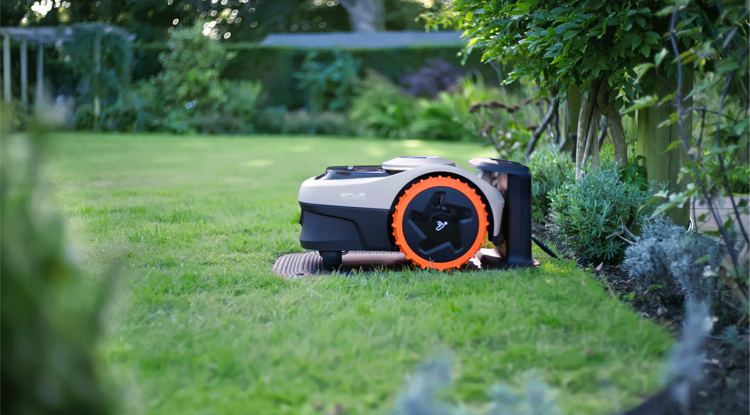 Segway Navimow i105 robotic lawn mower docked at its charging station in a landscaped backyard.