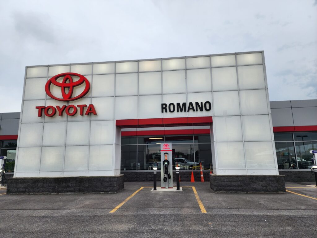 Electric vehicle charging station installed at Romano Toyota dealership entrance, featuring a ChargePoint Level 2 EV charger positioned beneath Toyota branding at the front of the showroom.