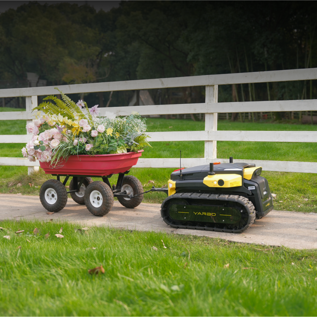 Yarbo autonomous yard robot towing a garden cart filled with flowers along a path